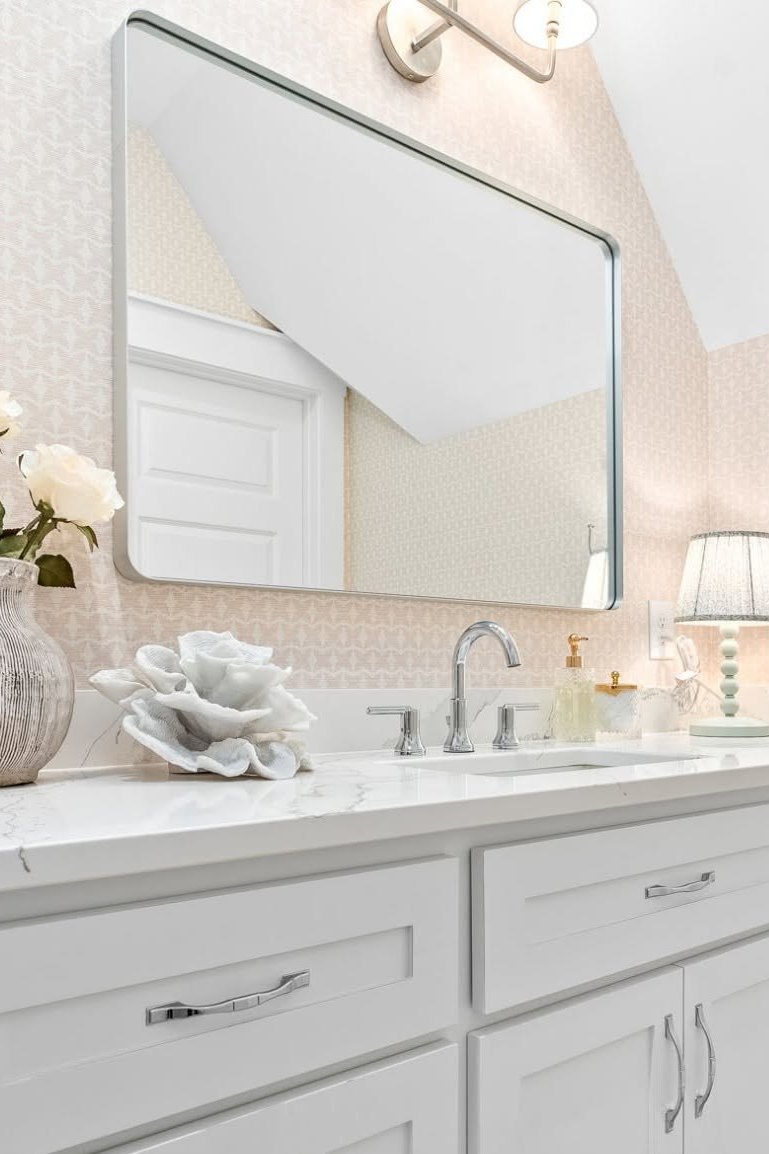 A bathroom vanity with an arched mirror and a brass picture light