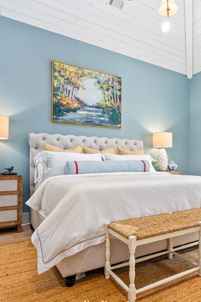 A blue bedroom with a four poster bed and layered bedding