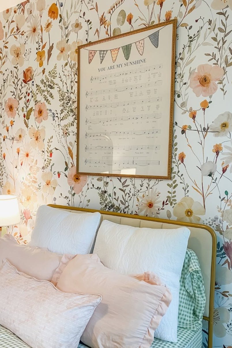 A bedroom with floral wallpaper and a scalloped upholstered headboard